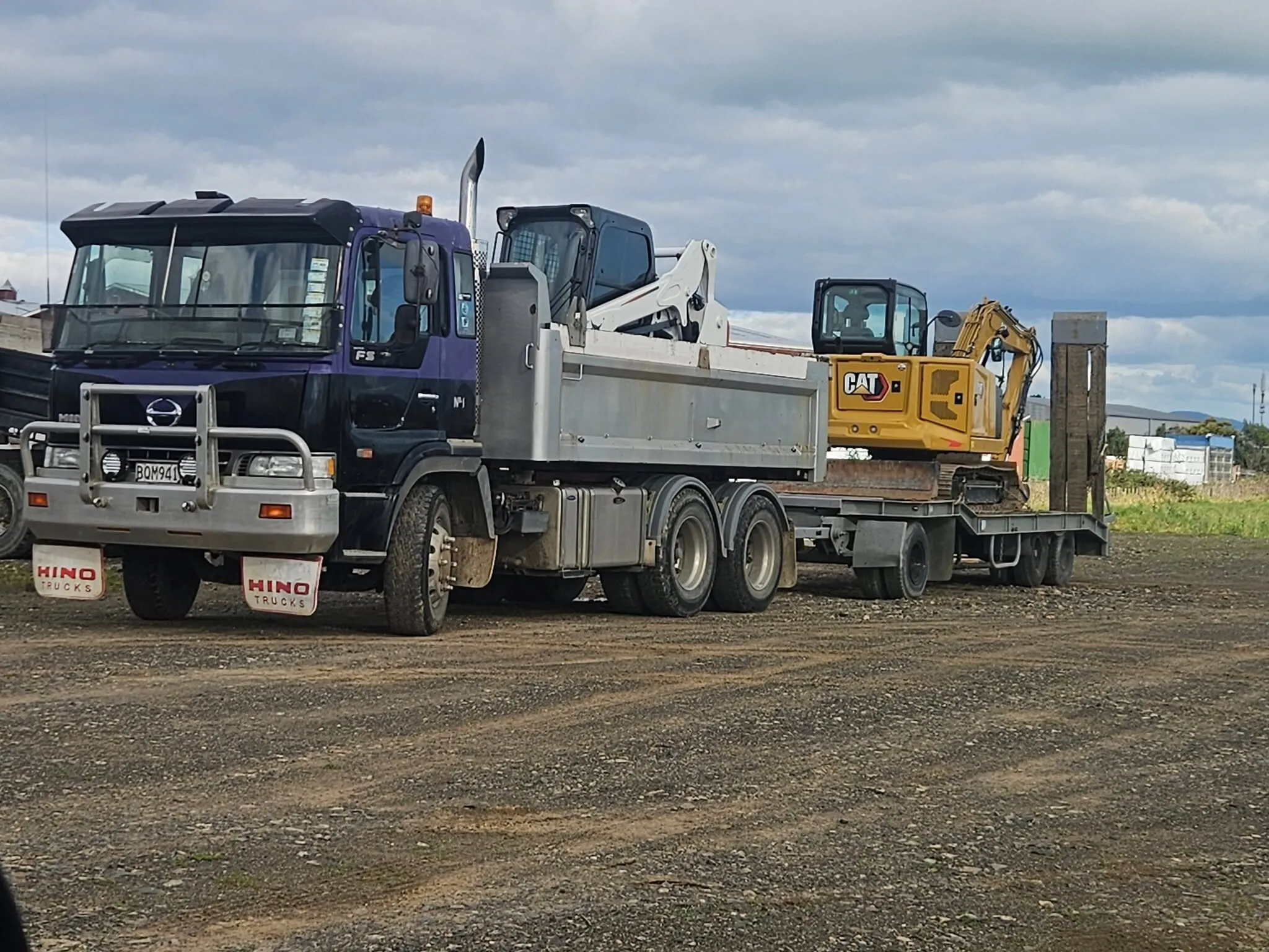 Tip truck loaded with a bobcat and mini excavator ready for transport